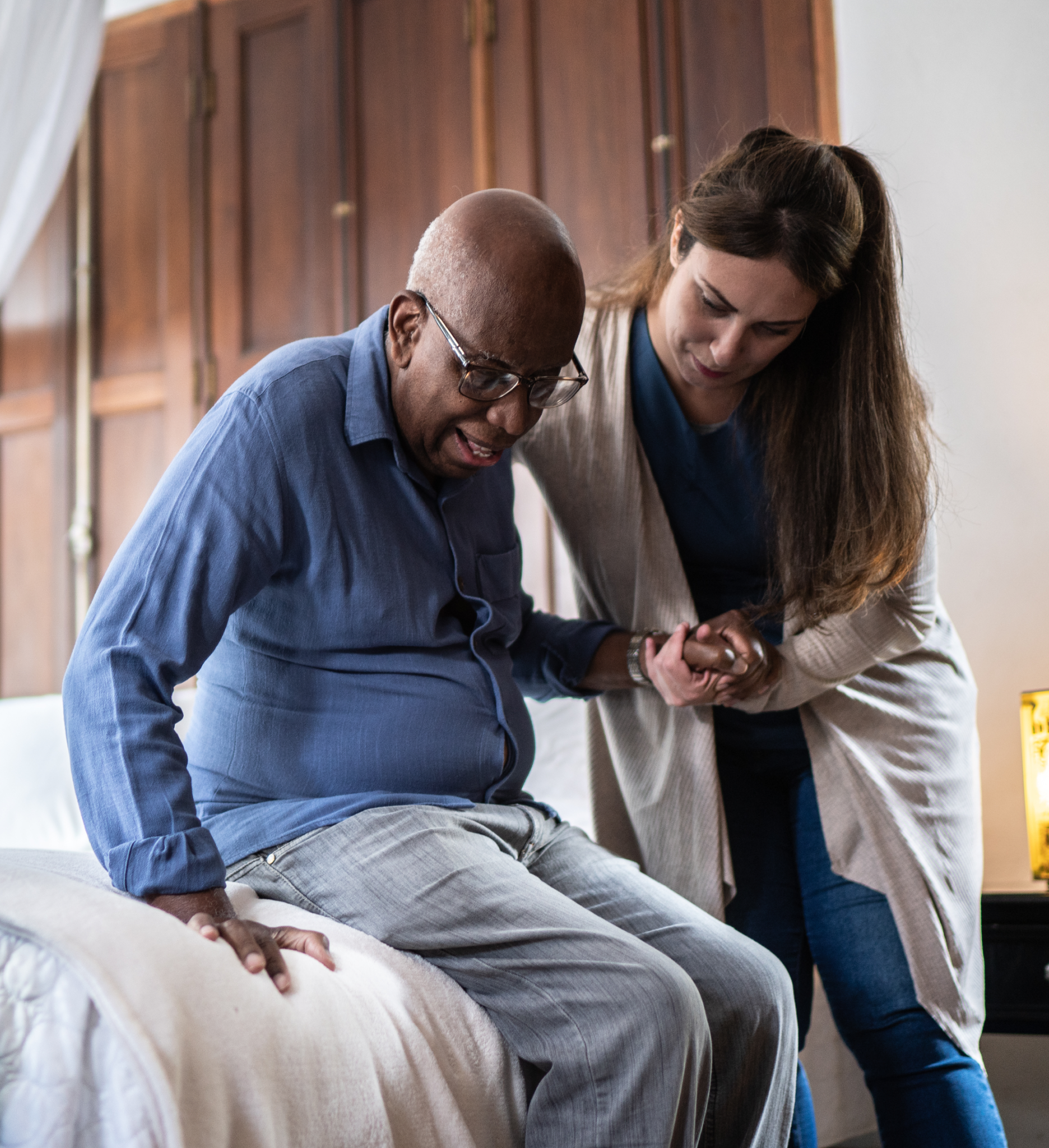 A home care nurse helps an elderly man out of bed