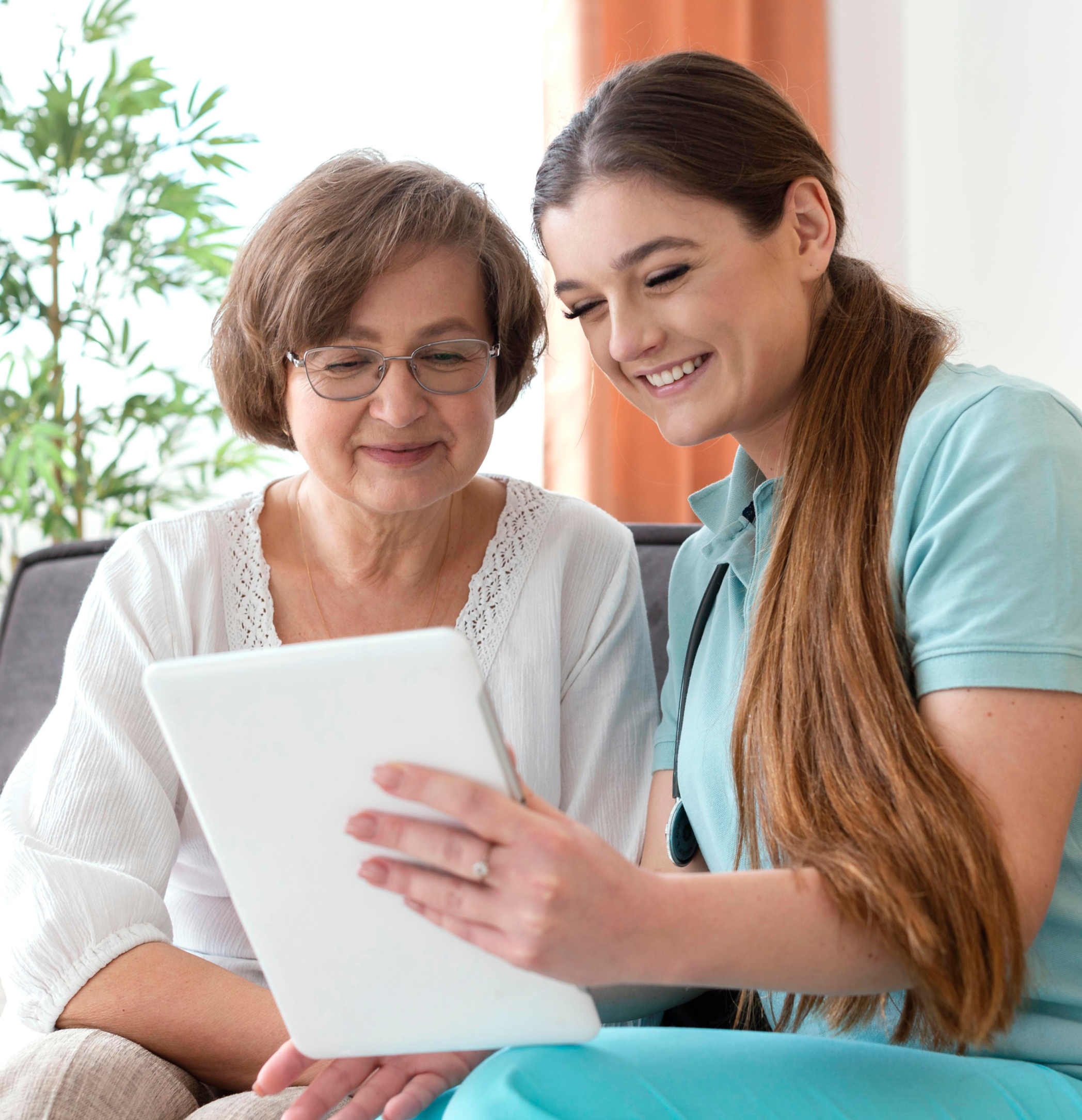 Two women sit together looking at a digital tablet